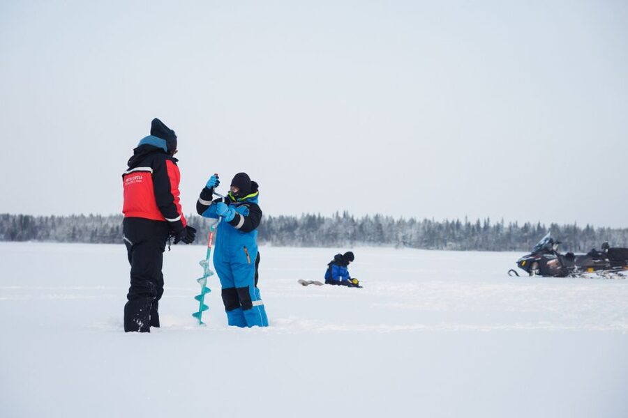 Rovaniemi: Ice Fishing & Snowmobile Safari Combo Day - Drilling through the frozen lake